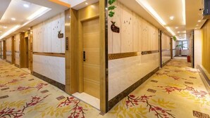 A hotel hallway with a floral carpet, wooden doors, and a sign above one door. - Seven Orange Hotel (Shenzhen North Station Minzhi) (Shenzhen)