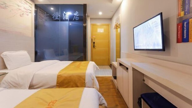 A hotel room with two beds, a television, a bookshelf, and a door leading to another room. - Seven Orange Hotel (Shenzhen North Station Minzhi) (Shenzhen)