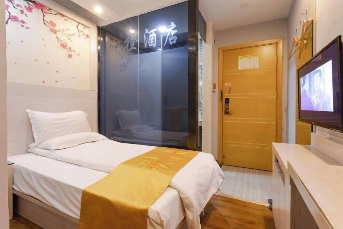 A hotel room with a bed, a television, and a wooden door.