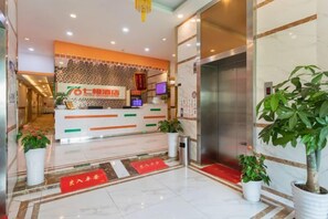 A hotel reception area with a reception desk, a digital screen, and a reception counter. - Seven Orange Hotel (Shenzhen North Station Minzhi) (Shenzhen)