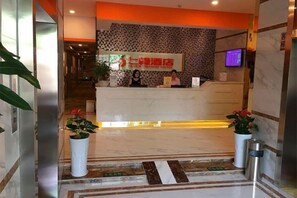A hotel reception area with a reception desk, a digital screen, and potted plants. - Seven Orange Hotel (Shenzhen North Station Minzhi) (Shenzhen)