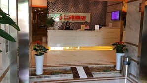 A hotel reception area with a modern design, featuring a reception desk, a wall-mounted television, and potted plants. - Seven Orange Hotel (Shenzhen North Station Minzhi) (Shenzhen)