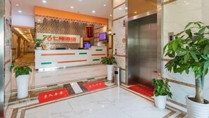 A hotel reception area with a reception desk, a digital screen, and a plant. - Seven Orange Hotel (Shenzhen North Station Minzhi) (Shenzhen)