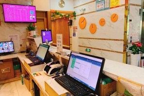 A reception desk with multiple computer monitors, a clock, and a wall-mounted calendar. - Seven Orange Hotel (Shenzhen North Station Minzhi) (Shenzhen)