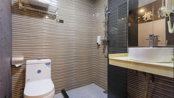A modern bathroom with striped tile walls, a white toilet, a sink with a mirror, and a towel rack.