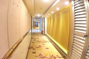 A corridor with a patterned floor, a radiator, and a door with horizontal slats.