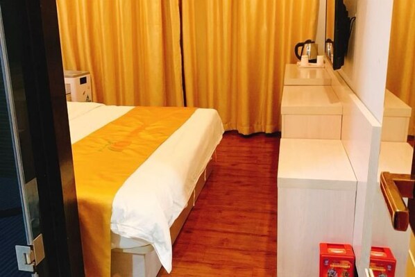 A hotel room with a bed, a desk, a mirror, and a window with curtains.