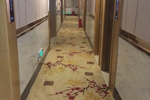A hotel hallway with a carpeted floor, a trash bin, and a door on the right. - Seven Orange Hotel (Shenzhen North Station Minzhi) (Shenzhen)