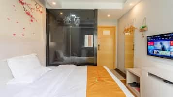 A modern hotel room with a bed, a TV, and a sliding door leading to a bathroom.