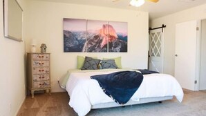 Ein Schlafzimmer mit einem Bett, einem Schminktisch, einem Gemälde und einer Tür.