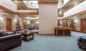 A spacious lobby with a high ceiling, wooden beams, and a central column. There are seating areas with sofas and armchairs, and a reception desk. - Charlie's Slopeside: Quiet Ski-In/Out, BC Village, Hot Tub, Sleeps 8, Walk to Ski School + Dining (Avon)