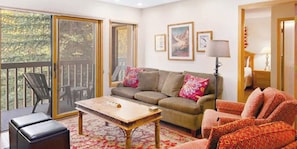 A living room with a sofa, a coffee table, and a chair. There is a sliding glass door leading to an outdoor area. - Charlie's Slopeside: Quiet Ski-In/Out, BC Village, Hot Tub, Sleeps 8, Walk to Ski School + Dining (Avon)