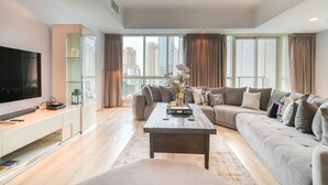 A modern living room with a flat-screen TV, a sofa, a coffee table, and a large window with curtains. - Alluring 2BR at Al Majara 1 Dubai Marina by Deluxe Holiday Homes (Dubai)