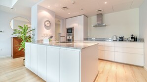 A modern kitchen with a central island, built-in appliances, and a large mirror. - Alluring 2BR at Al Majara 1 Dubai Marina by Deluxe Holiday Homes (Dubai)