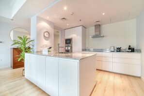 Une cuisine moderne dotée d’un îlot central, d’appareils électroménagers intégrés et d’un grand miroir.
