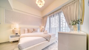 Ein modernes Schlafzimmer mit einem großen Bett, Nachttischen, einem Spiegel und einer Topfpflanze.