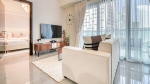 Ein modernes Wohnzimmer mit einer Couch, einem Fernseher und einem großen Fenster mit Vorhängen.