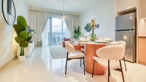 A modern kitchen with a central island, dining chairs, and a refrigerator.