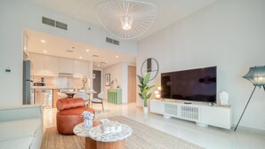 A modern living room with a sofa, coffee table, and a TV on a white stand.