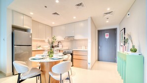A modern kitchen with a central island, stainless steel appliances, and a dining area with chairs.