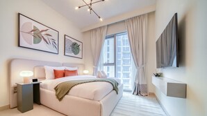 A modern bedroom with a large bed, bedside tables, a TV mounted on the wall, and artwork on the walls.