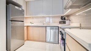Una cocina moderna con electrodomésticos de acero inoxidable, lavavajillas y microondas.