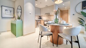 Una cocina moderna con una isla central, electrodomésticos integrados y un comedor con sillas y mesa.