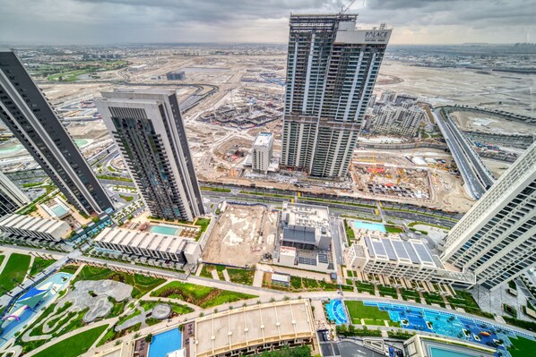 A high-rise building with multiple floors, surrounded by other tall buildings, a swimming pool, and a landscaped area.