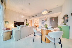 Une cuisine moderne dotée d’un coin repas, avec un îlot central, des chaises de couleur claire et un décor contemporain.