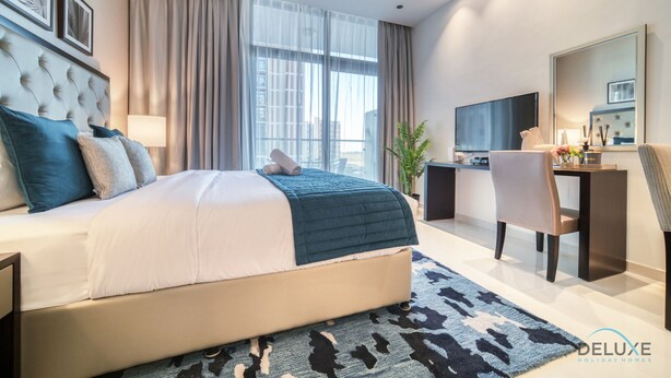 Ett modernt hotellrum med en stor säng, ett skrivbord, en TV och utsikt över staden.