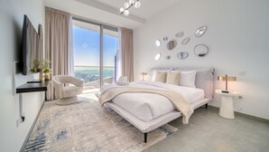 Un dormitorio moderno con una cama grande, un televisor, una silla y vistas a la ciudad.