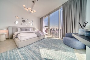 A modern hotel room with a large bed, a desk, and a view of the city.