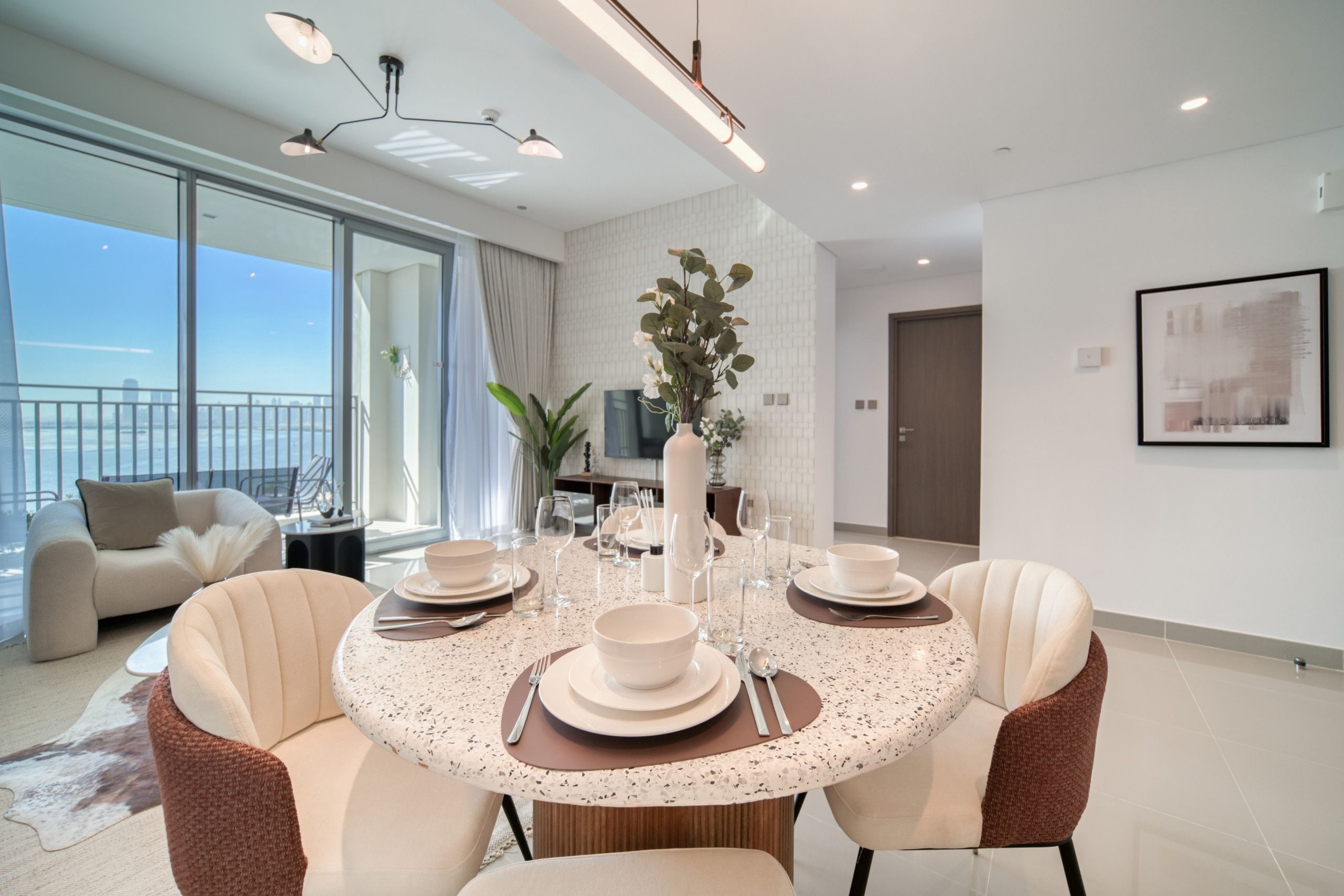 A modern dining area with a round table set for four, surrounded by comfortable seating.