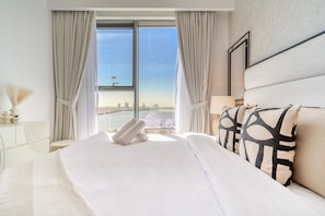 A hotel room with a large bed, a view of a body of water, and a cityscape.