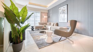 Un salon moderne avec un canapé, un fauteuil, une table basse et une grande plante en pot.