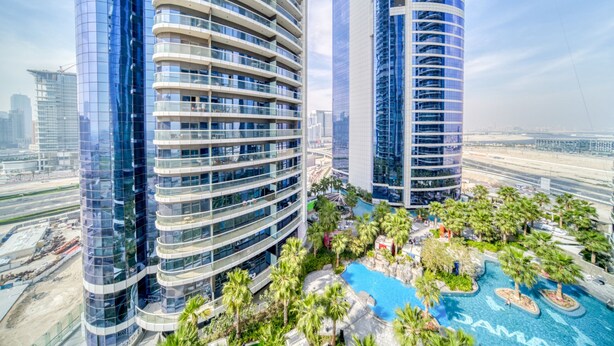 Un hôtel moderne à la façade incurvée, doté d’une piscine sur le toit et d’un aménagement paysager luxuriant.