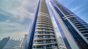 Un immeuble moderne de grande hauteur, doté d’une façade incurvée, entouré d’autres bâtiments imposants.