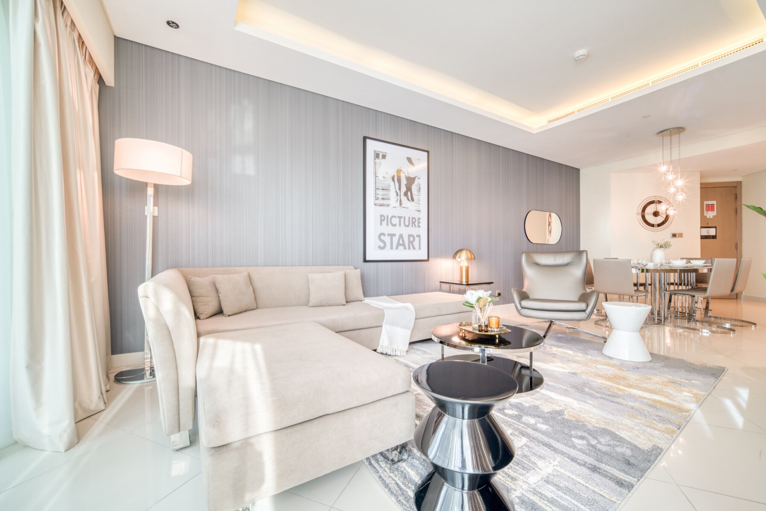 Ein modernes Wohnzimmer mit einem beigefarbenen Ecksofa, einem runden Couchtisch und minimalistischer Einrichtung.