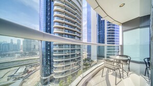 Un balcon moderne avec une balustrade en verre donnant sur un paysage urbain et un chantier de construction.