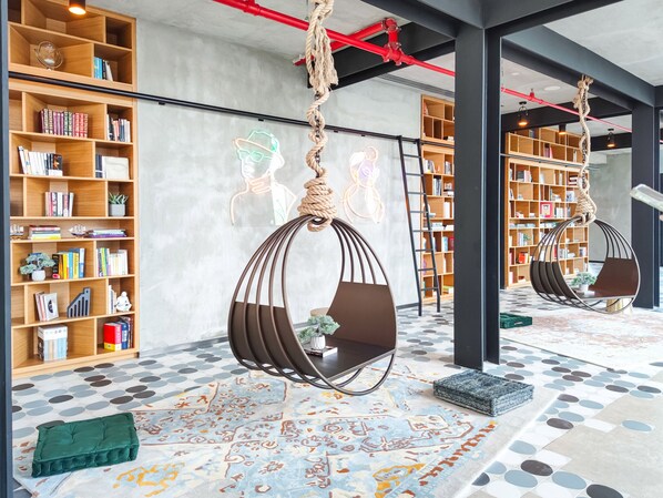 A modern library with bookshelves, hanging chairs, and a patterned floor.