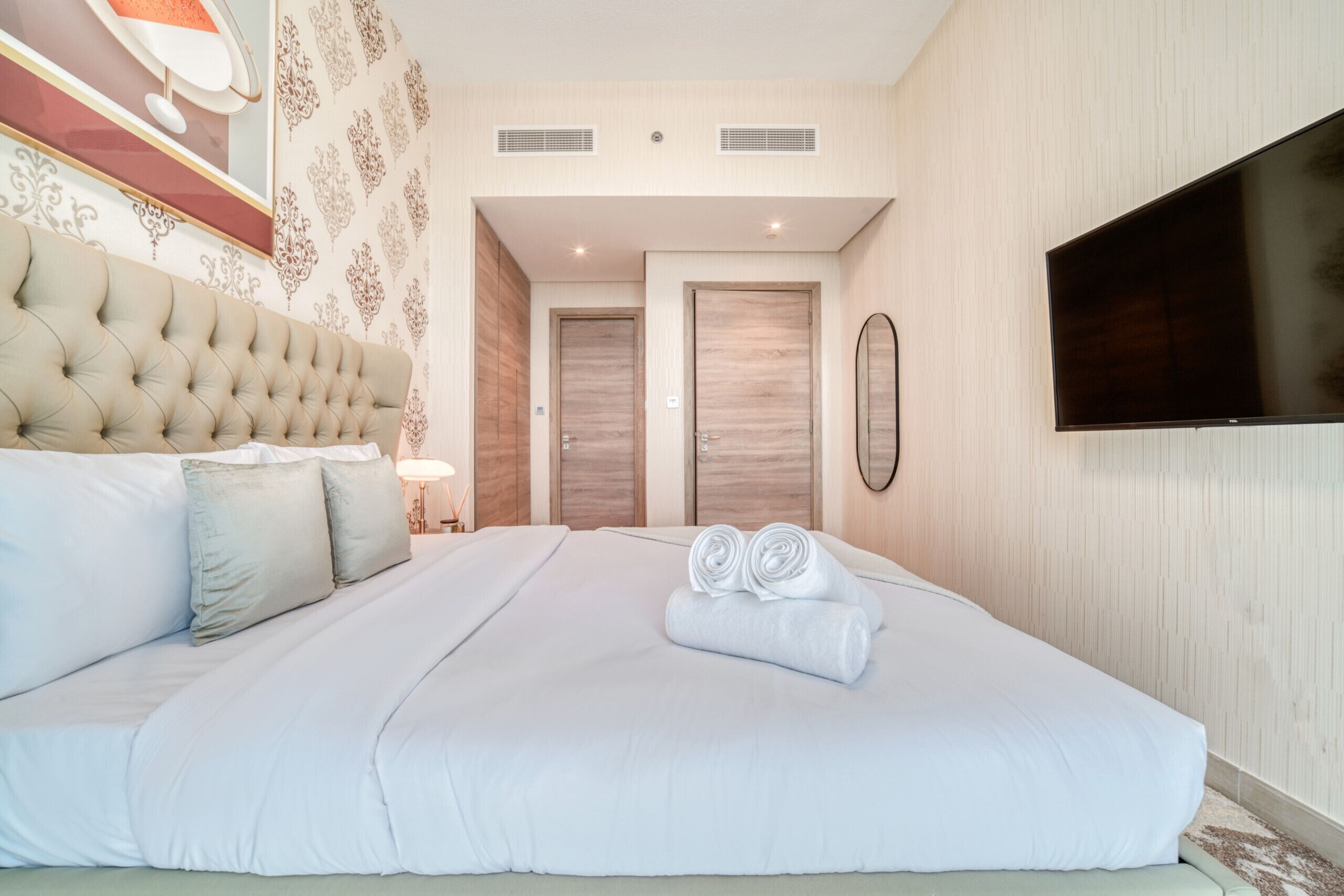 Una habitació d'hotel moderna amb un llit gran, una televisió de pantalla plana i un panell decoratiu a la paret.