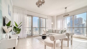 Ein modernes Wohnzimmer mit einer Couch, einer Katzenliege, einem Couchtisch und großen Fenstern mit Blick auf die Stadt.