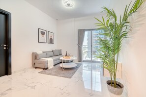 Un salon moderne avec un canapé, une table basse et une grande plante en pot.