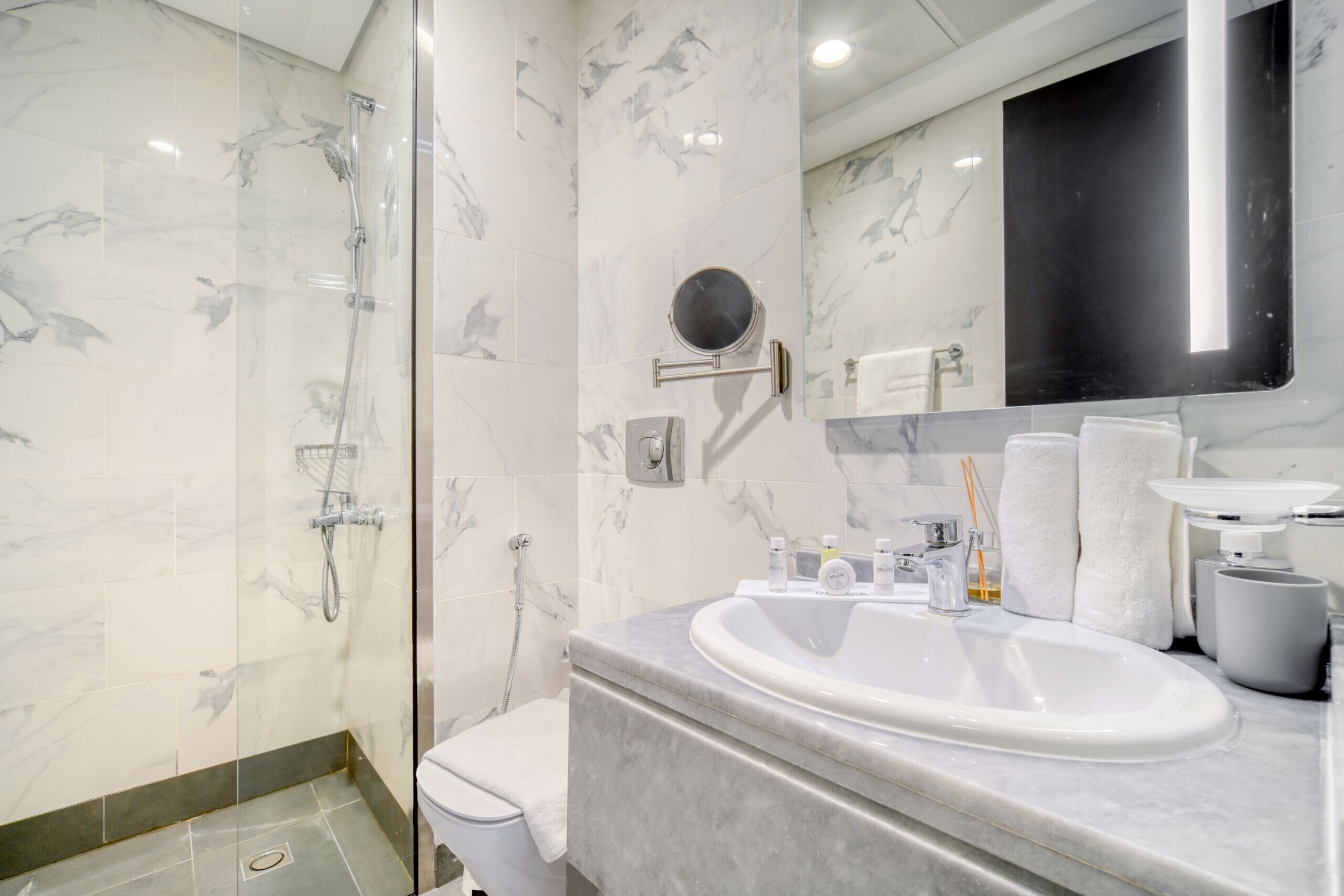 A modern bathroom with a glass-enclosed shower, a large sink, and a mirror above the sink.