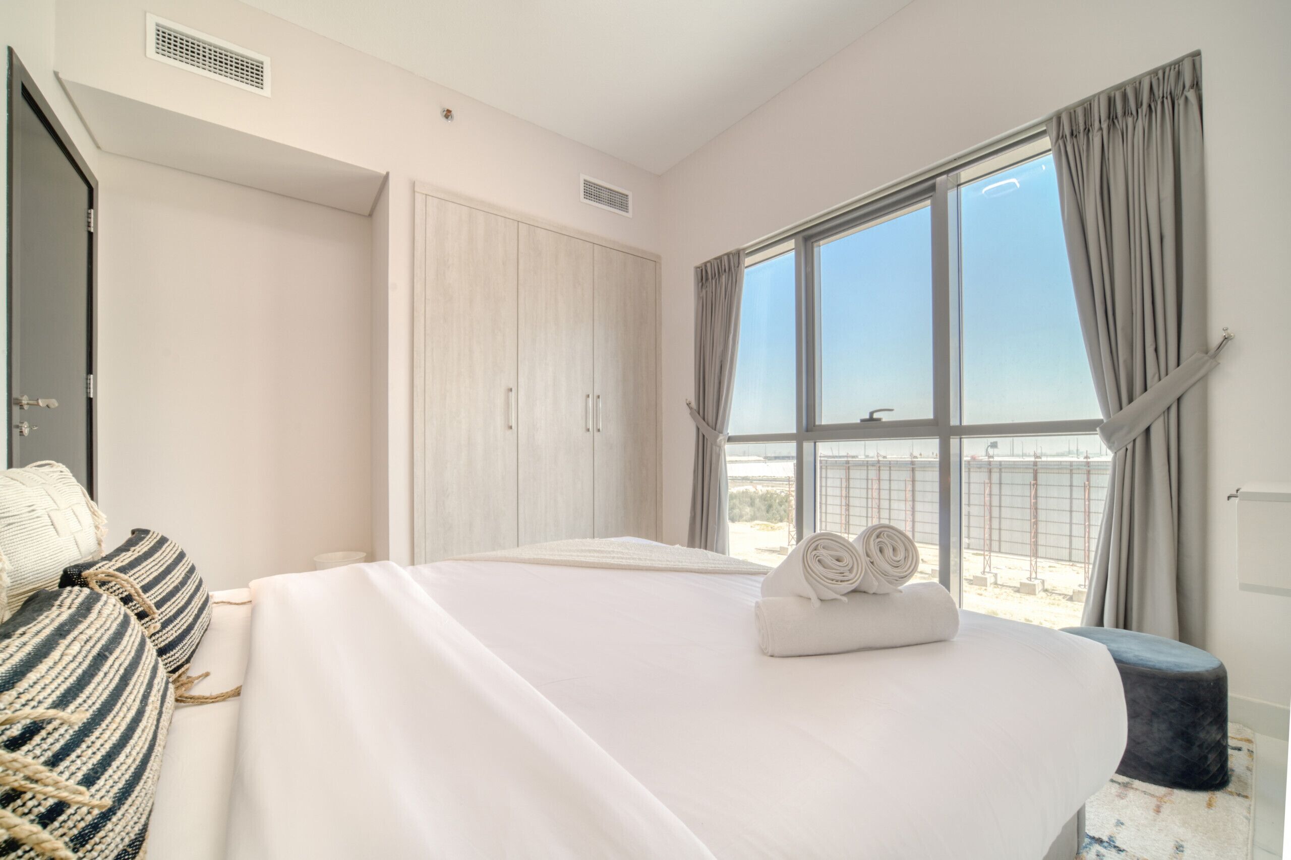 Camera d'albergo con un letto grande, un armadio, una finestra con tende e vista sull'esterno.