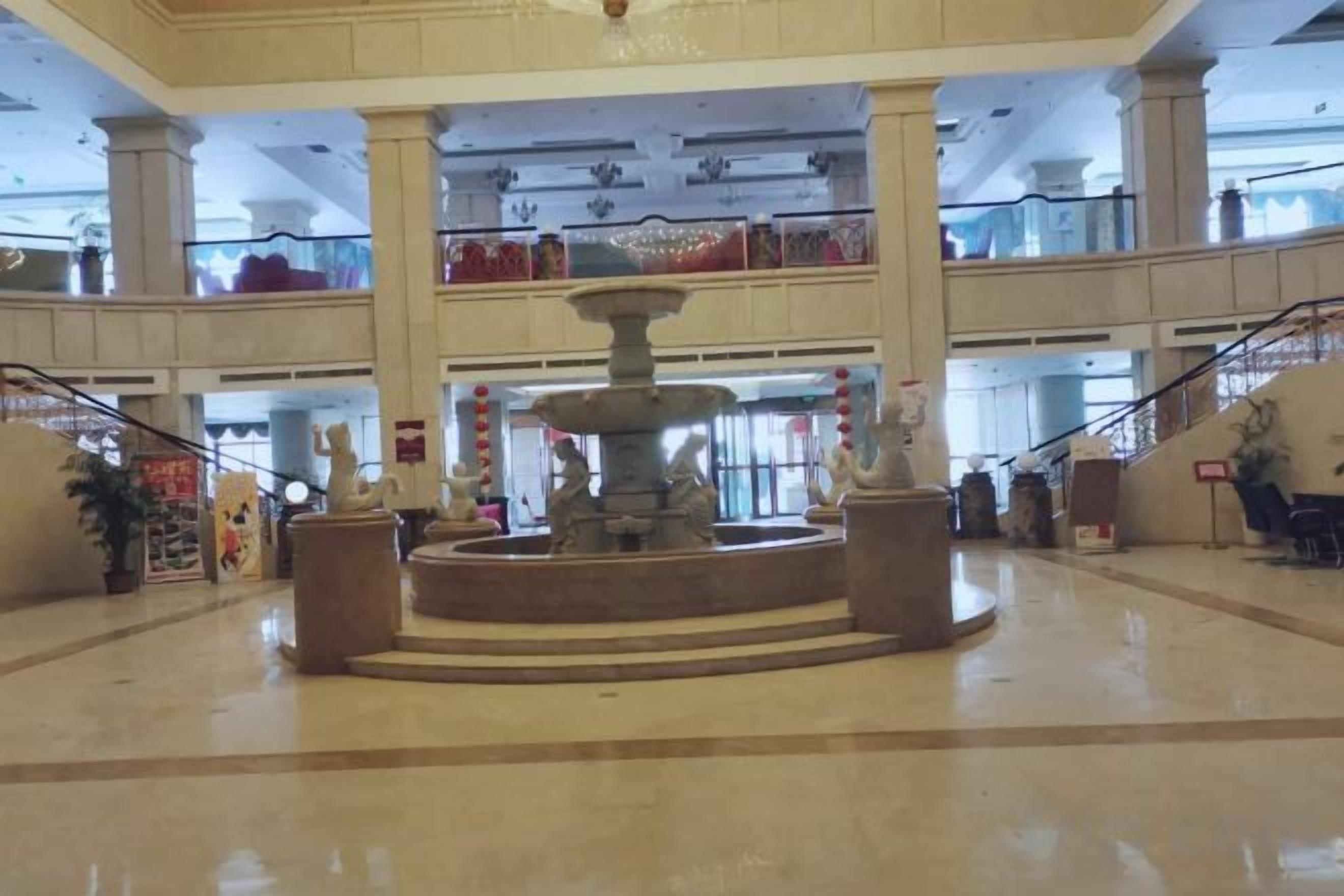Un amplio atrio con una fuente central, varios niveles y una escalera.