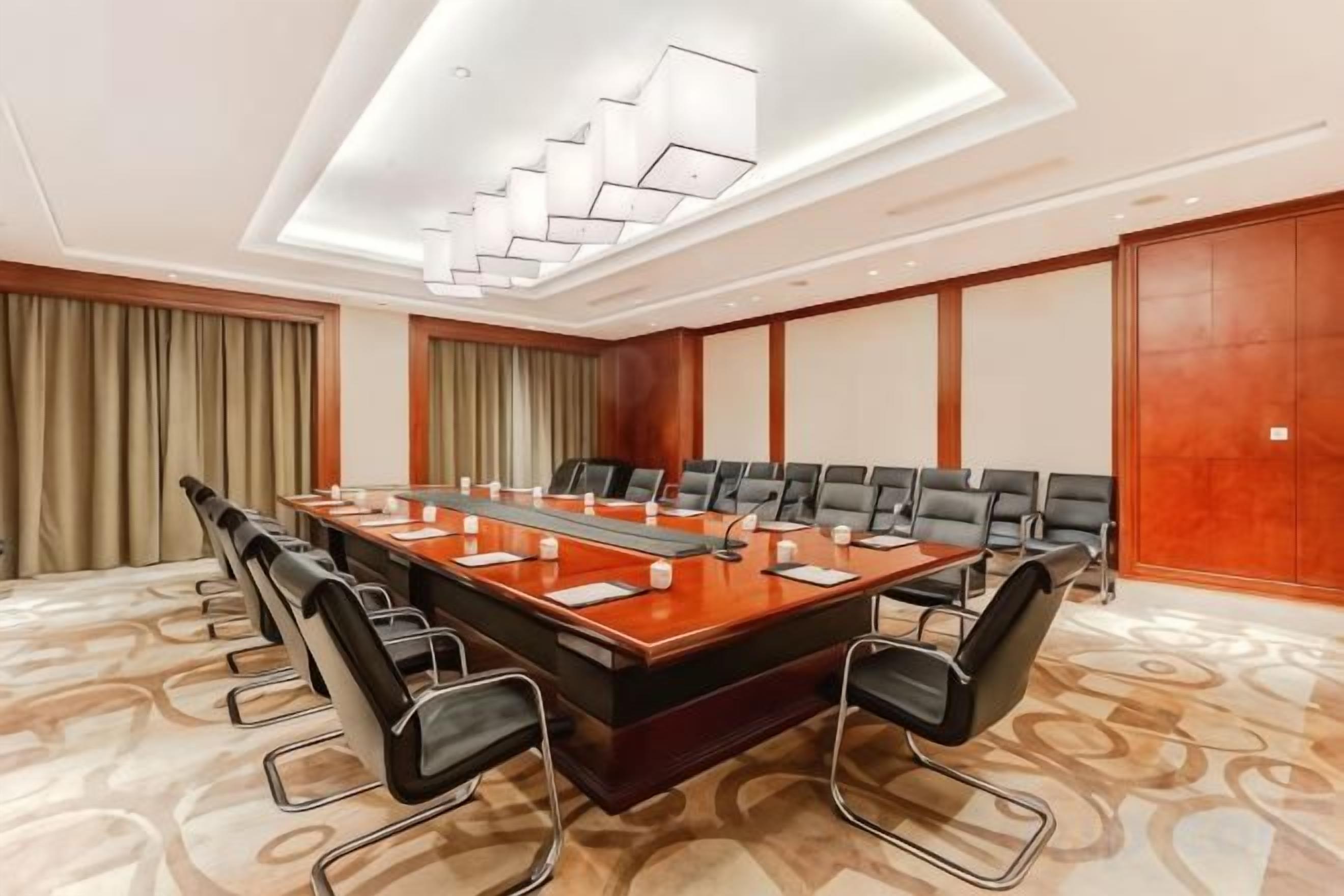 A conference room with a long table, multiple chairs, and a modern chandelier.