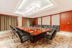 A conference room with a long table, multiple chairs, and a modern chandelier. - Hongxing International Hotel (Jing County)