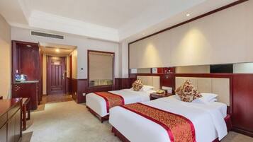 Quarto de hotel com duas camas, uma escrivaninha e um mini-bar.
