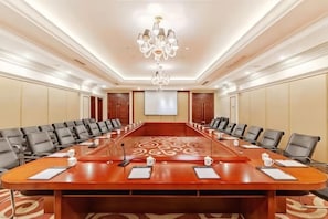 A conference room with a long table, chairs, a projector screen, and a chandelier. - Hongxing International Hotel (Jing County)